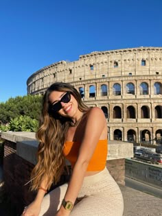 a woman posing in front of the colossion with her hand on her hip