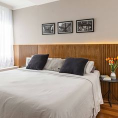 a white bed sitting in a bedroom next to two pictures on the wall above it