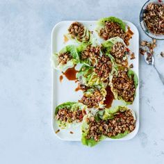 lettuce with meat and sauce on a white plate next to a bowl of dressing