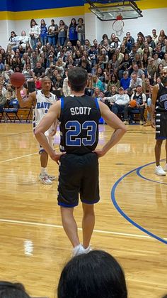 a basketball player standing on the court in front of an audience with his back to the camera