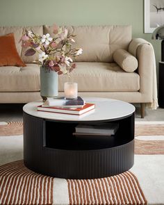 a living room with a couch, coffee table and flowers in a vase on top