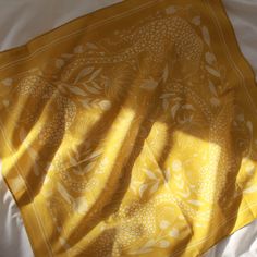 a yellow and white blanket laying on top of a bed next to a window with the sun shining through it