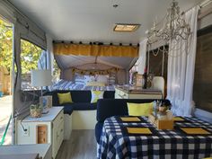 the inside of a camper with blue and yellow decor on the table, couches, and windows