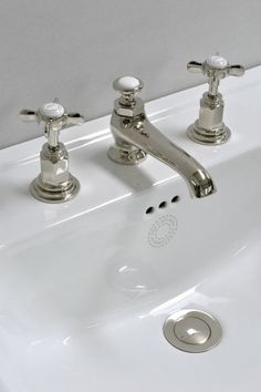 two chrome faucets on a white sink in a bathroom