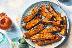 there is a plate full of chicken wings on the table next to glasses and bottles