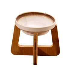 a white bowl sitting on top of a wooden stand in front of a white background