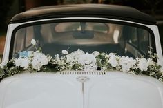 an old white car decorated with flowers and greenery