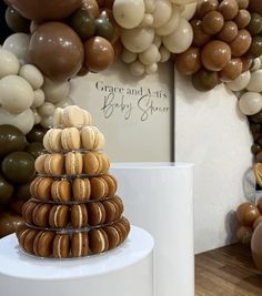 there is a cake made out of macaroons on the table and balloons in the background