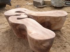 two wooden benches sitting on top of a sandy ground next to rocks and wood planks