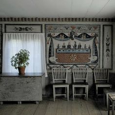 an old room with several chairs and a potted plant on the table in front of a window