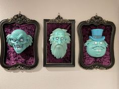 three masks are hanging on the wall next to each other in frames with purple velvet