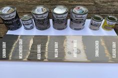 several cans of paint sitting on top of a white table next to a wooden board