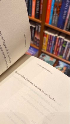 an open book sitting on top of a table in front of a bookshelf