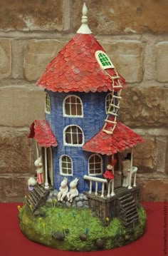 a blue house with red roof sitting on top of a table