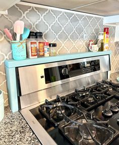 a stove top oven sitting inside of a kitchen next to a wallpapered backsplash