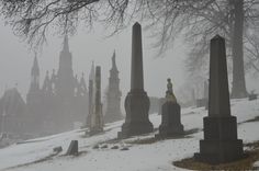 an old cemetery with snow on the ground and tall spires in the backgroud