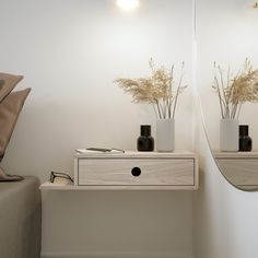 two vases with flowers are sitting on a shelf in front of a mirror and a couch