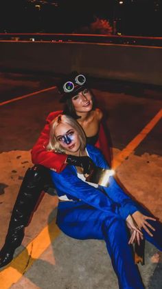 two people dressed up in costumes posing for a photo on the street at night time