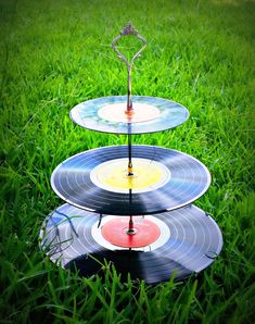 three tiered trays with vinyl records on them sitting in the middle of grass