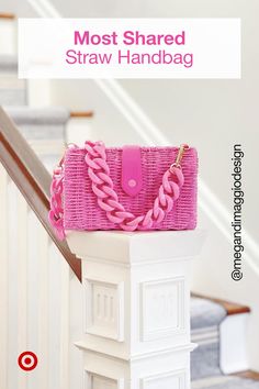 a pink handbag sitting on top of a white stair case next to a banister