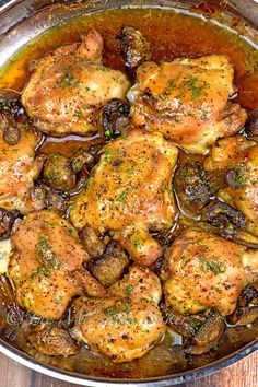 chicken with mushrooms and herbs in a pan on a wooden table, ready to be cooked