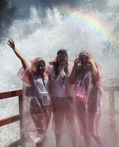 three girls are standing in the water with their arms up