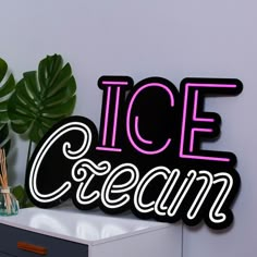 a neon ice cream sign sitting on top of a white table next to a potted plant