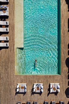 an aerial view of a pool with lounge chairs and people swimming in the water near it