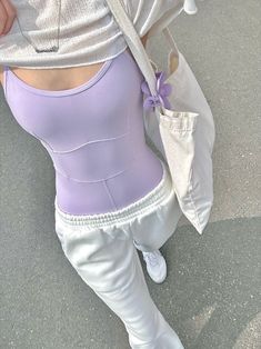 a woman in white pants and a purple top is holding an umbrella over her head