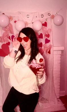 a woman wearing heart shaped glasses holding a drink