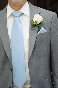 a man in a gray suit with a blue tie and white rose boutonniere