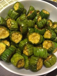 green peppers with yellow sauce in a white bowl on a counter top, ready to be eaten