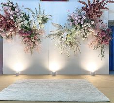 three vases with flowers are sitting on the floor in front of a white wall