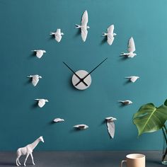 a clock that is on the wall next to a plant and a vase with a toy giraffe