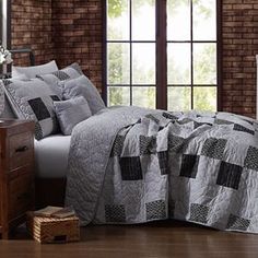 a bed in a room with brick walls and wooden flooring next to a window