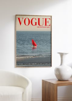 a magazine cover with a red sailboat on the water in front of a white chair