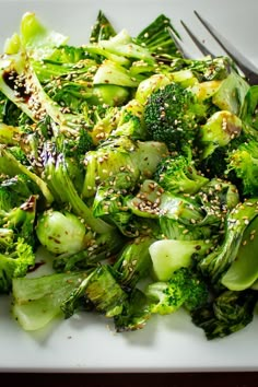 a white plate topped with broccoli covered in sesame seeds