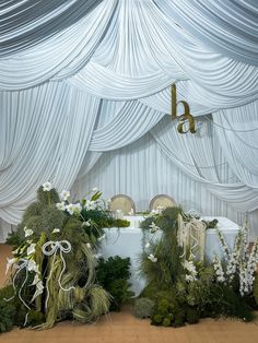 the table is covered with white flowers and greenery for an elegant wedding or special event