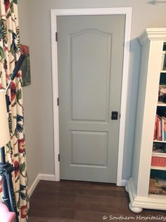 a white door in a room next to a book shelf with books on the shelves