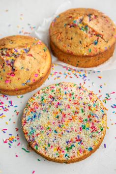 three cakes with sprinkles on top of white paper