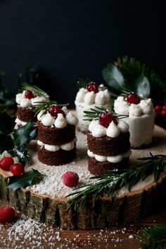 small cakes with white frosting and cranberry toppings on a wood slice