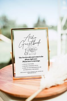 a sign that is sitting on top of a wooden table next to a white feather