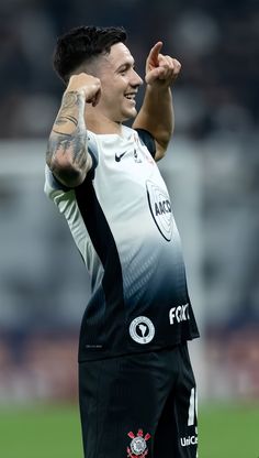 a man with his arm in the air, wearing black and white soccer shorts while standing on a field