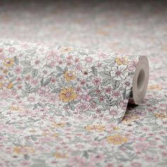 a roll of toilet paper sitting on top of a flowery floorcloth covered in pink, yellow and white flowers