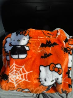 an orange hello kitty blanket sitting in the back seat of a car with halloween decorations on it