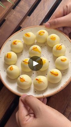 a person is holding a plate with small desserts on it and the video appears to be playing