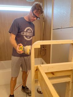 a man is sanding up some wood in the bathroom while using a power drill