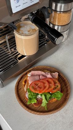 a sandwich on a wooden plate next to an espresso machine