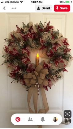 a christmas wreath with a lit candle hanging on the front door's handlebar