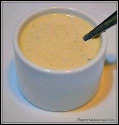 a white bowl filled with soup on top of a table next to a black spoon